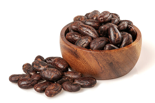 Organic roasted cacao beans in small wooden bowl. Natural superfood ingredient for chocolate production and healthy snacks isolated on white background.
