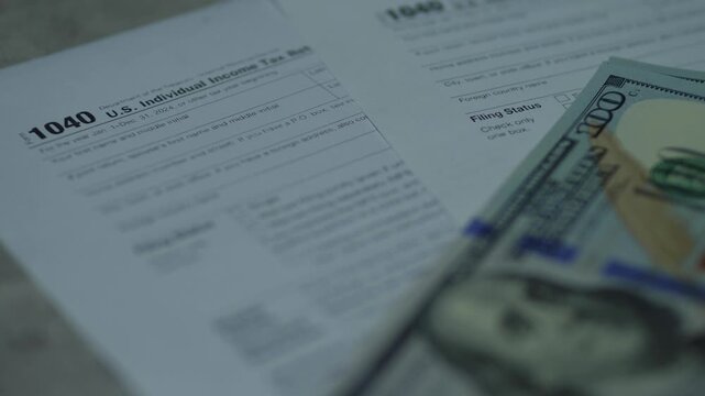 Close-up of US Individual Income Tax Return form 1040 with hundred dollar bills. Concept of tax preparation, financial reporting and tax refund