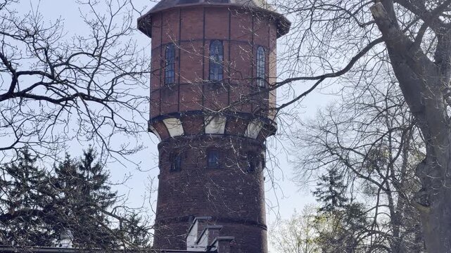 Historic brick water tower behind bare branches panning