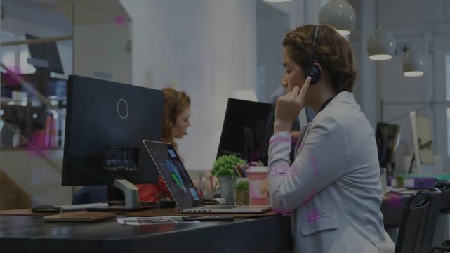 Service rep wearing headset helping customer, answering call, pointing to laptop, typing