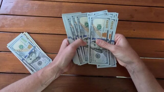Woman hands counting stack of 100 dollar bills at table, leafing through banknotes. Close-up. Concept of making money. Accumulated capital. Financial planning, savings. 