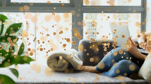 Woman settling on window-seat, bringing laptop, typing with bokeh overlay over plant, her for work