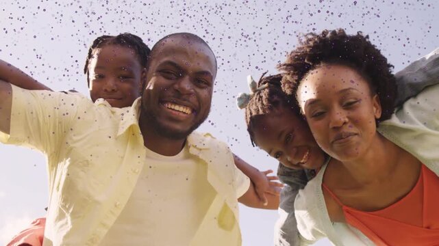 Low camera inviting family leaning over lens, parents spreading arms, children peeking, marketing