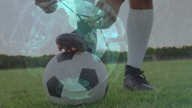 Male sportsman lifting foot threading laces on boot over ball, tying knot with cyan globe overlay