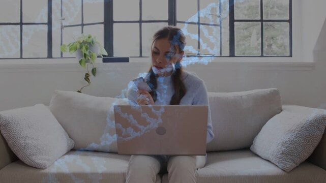 Woman placing laptop and causing DNA helix overlay while juggling phone and laptop for health work