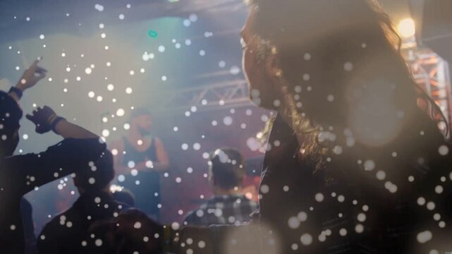 Crowd raising hands and swaying at live music performance, performer dropping beat, lights flaring