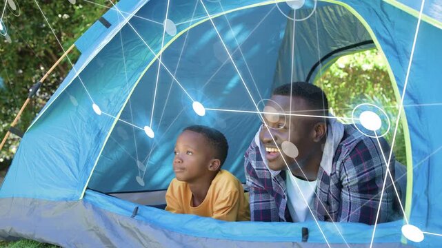 Father-son lying tent, child pointing out curious causing father leaning technology overlay growing