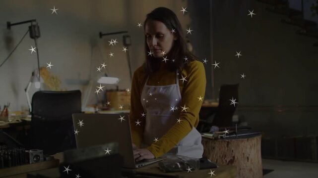 Craftswoman at laptop starting work placing hands, typing while star sparkles partly obscuring
