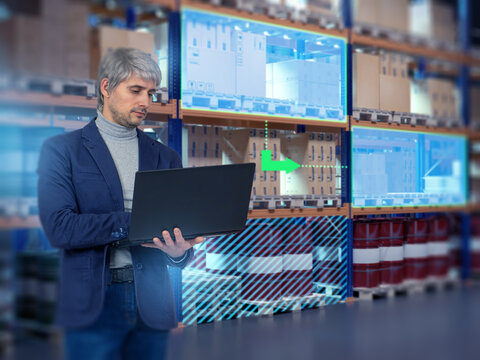 Warehouse analytics, smart logistics. Specialist uses laptop to monitor inventory flow with digital interface, optimizing storage, tracking goods and managing automated operations.