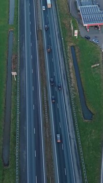 Vertical screen Aerial View Of Road And Fuel Station. Overhead Perspective Of Highway Near Service Area. Aerial Photograph Capturing Roadway Alongside Fuel Station With Vehicles Present