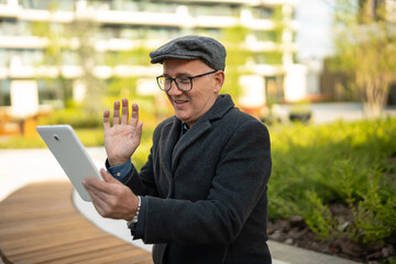 Mature man waving hand during video call on tablet © Jelena