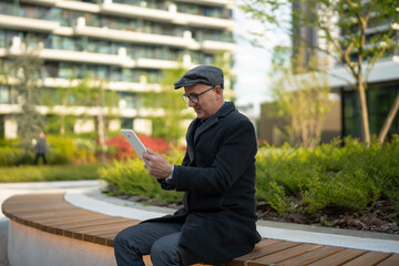 Obraz premium Mature man using digital tablet sitting outdoors