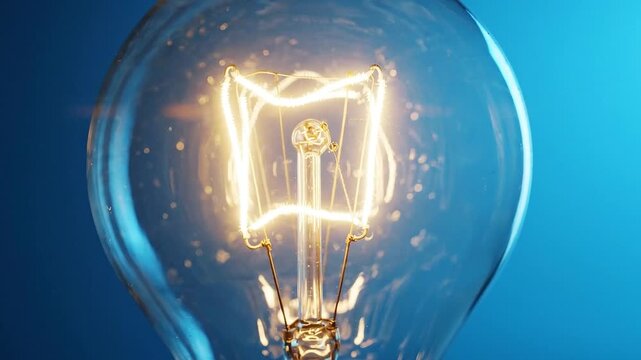 Closeup of a lit incandescent light bulb with a blue background