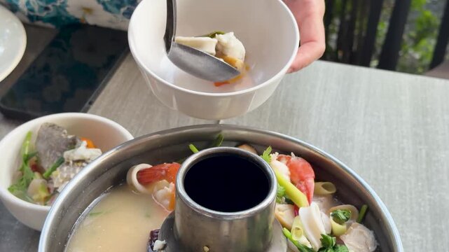 Serving Spicy Thai Seafood Tom Yum Soup From Metal Hot Pot