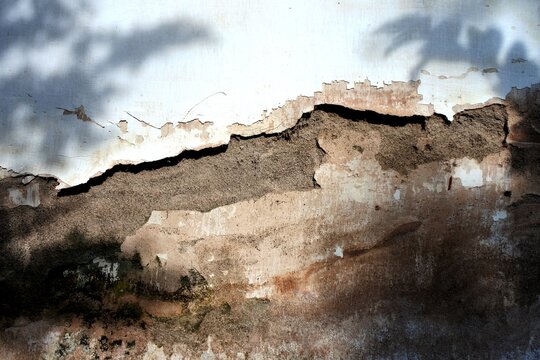 The old building walls with peeling paint and plaster that has crumbled due to high humidity