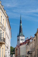 Fototapeta premium Church steeple towers over pastel colored buildings in Tallinn Estonia