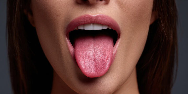 Close up mouth with pink tongue and open lips in studio portrait, showing healthy teeth and smooth skin
