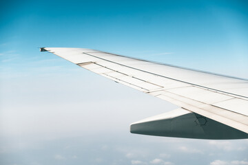 Fototapeta premium Airplane wing flying high in blue sky clouds