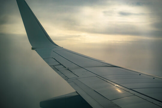 Airplane wing in cloudy moody sky at sunset