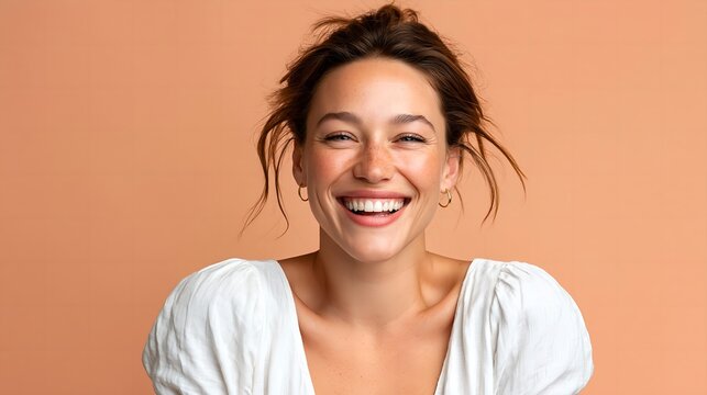 Woman smiles broadly. Hair is loose and tousled. Eyes sparkle with joy. Light, natural expression
