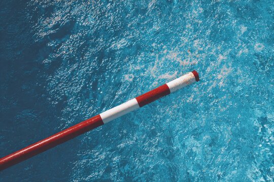 Red and White Pole Extending Over Rippling Blue Water Surface.