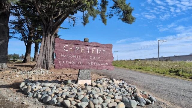 Wooden sign marking Catholic, Veterans, and IOOF sections of a cemetery. Highlights local history and the intersection of fraternal orders and military service.