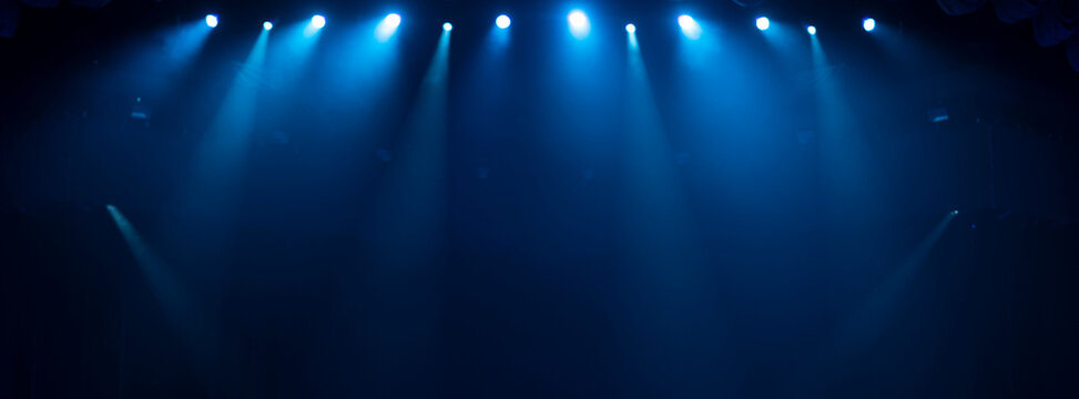 Panoramic blue stage lights background with beams and copy space