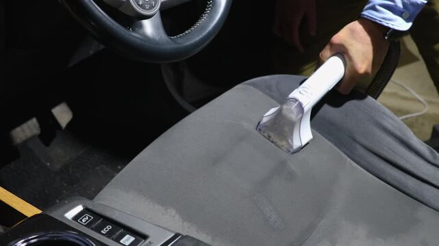 自動車の運転席のシートをリンサークリーナーで洗浄している