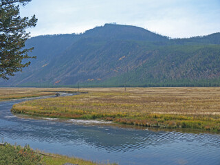 Obraz premium Yellowstone National Park autumn scenery with Firehole River and yellow dry grass field on sunny day