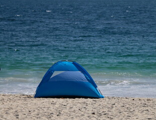 Blue tent on beach with ocean in back © Evi