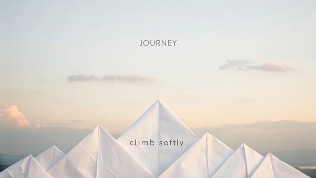 Minimalist artistic representation of mountains made from white paper, featuring a calm sky and gentle pastel colors during sunset or dawn