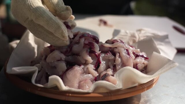 Cinematic slow motion of fresh sashimi being plated, piling up raw fish slices