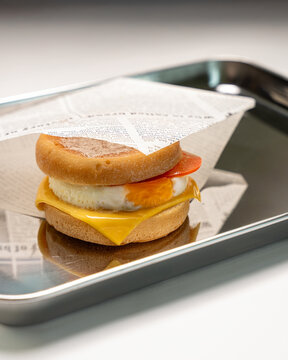 Breakfast egg muffin sandwich on metal tray with cheese and tomato