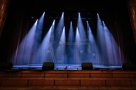 Stage setup with multiple spotlights illuminating a performance area, featuring a wooden floor and backdrop curtains in a theater environment