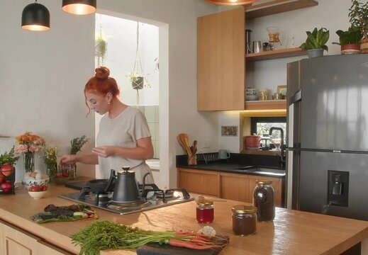 Red haired woman preparing fresh vegetables in cozy modern kitchen, healthy cooking lifestyle