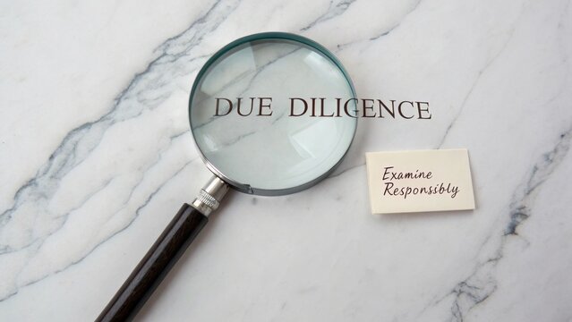 Magnifying Glass Over Due Diligence Text on Marble Surface with Examination Note Emphasizing Responsibility in Business Practices
