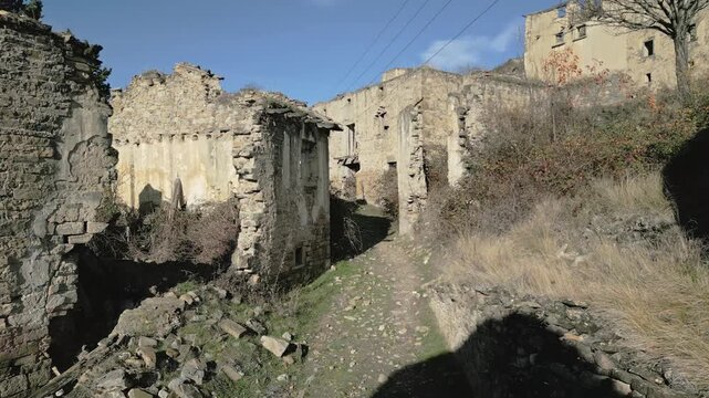 Ruined stone buildings and overgrown streets of the abandoned ghost town of Esco, a desolate historical site in the Aragon region of Spain, showing the effects of decay and depopulation