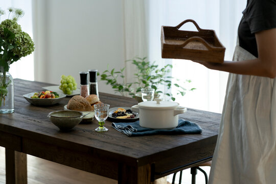 朝食がのった食卓とトレイを持った女性