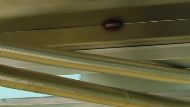 Golden, flexible tubes are intricately connected on an industrial air filtration system outdoors. These corrugated conduits help purify the atmosphere, shining brightly under the blue daylight sky.