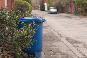 Obraz premium Blue plastic recycling bin for paper waste stands at the roadside in the suburbs