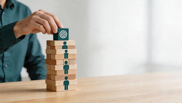 Business man stacking wooden blocks to build team structure organizational hierarchy concept with target symbol on top block for management strategy and leadership goals corporate