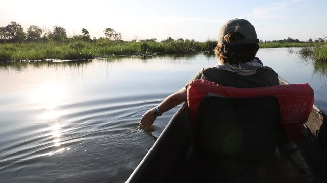 child's hand touching delta water, Okavango Delta, Botswana, Africa