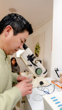 Man examining optical lens using a microscope
