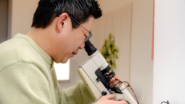 Optician using microscope in optical laboratory