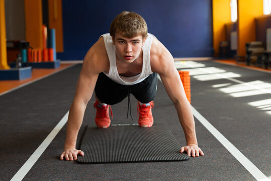 Young athlete training on gym mat for fitness