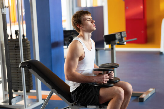 Determined young athlete lifting dumbbells at gym