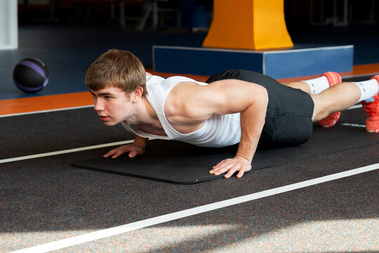 Young sportsman performing push-ups in gym setting