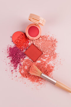 Makeup blushes and brush arranged on pink background