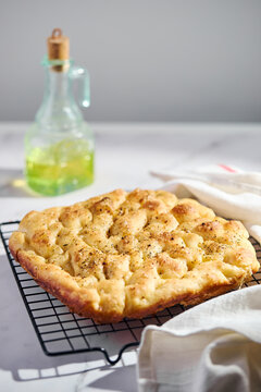 Fresh focaccia flatbread cooling on rack with olive oil