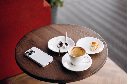 Cozy cafe table with coffee cup, pastry and smartphone